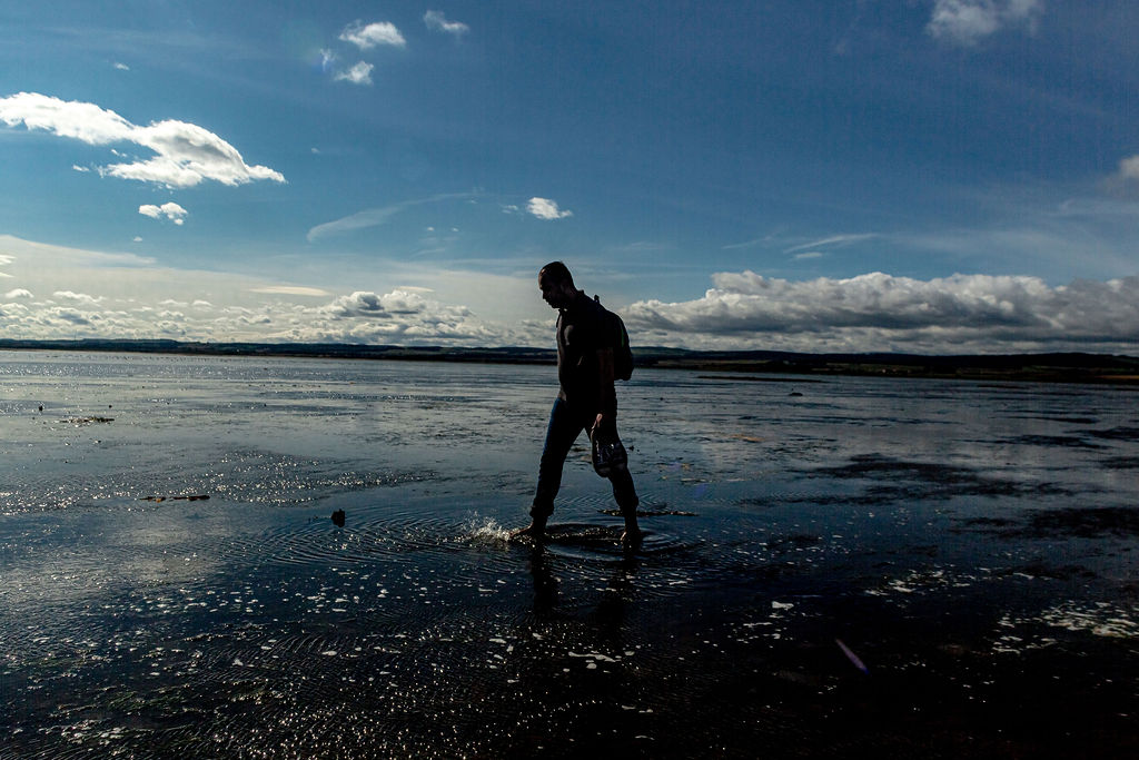 A person walking barefeet in water on the Pilgrim’s Way.